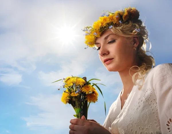 Hermosa mujer con flores de diente de león sobre el cielo azul —  Fotos de Stock