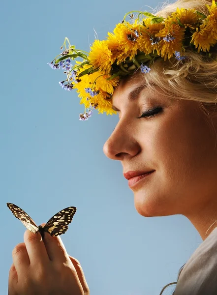 Härlig kvinna med en fjäril under blå himmel — Stockfoto