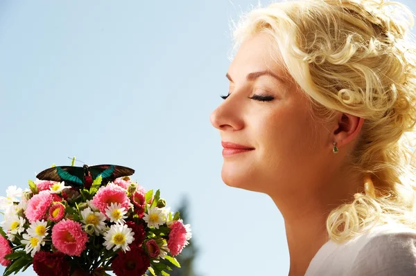 Piękne blond kobieta z świeżych kwiatów i motyli — Zdjęcie stockowe