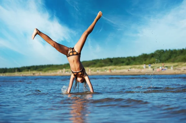 Mladá dívka dělat přemet stranou ve vodě — Stock fotografie
