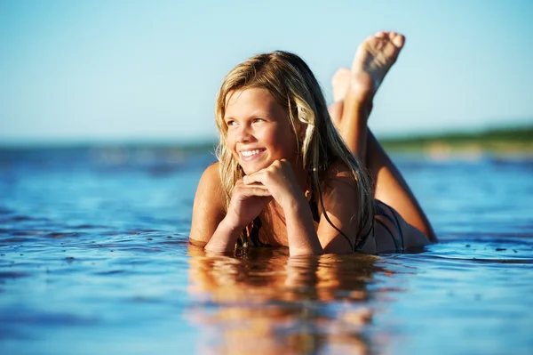 Menina feliz deitada na água — Fotografia de Stock
