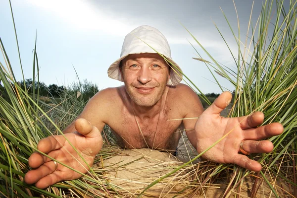 Homme drôle regardant à travers l'herbe — Photo