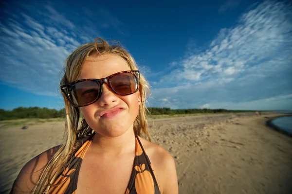 Mladá dívka na pláži a legrační obličej — Stock fotografie