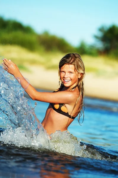 Joven chica feliz haciendo salpicaduras de agua — Foto de Stock