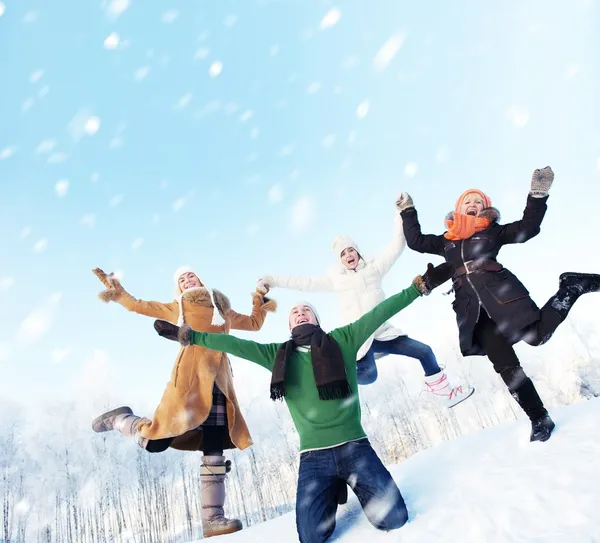 Happy friends jumping in the snow — Stockfoto