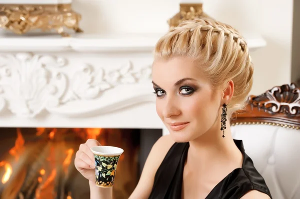 Блондинка пьет кофе в роскошном интерьере — стоковое фото