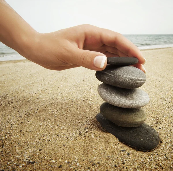 Woman hand touching stones on the beach — Stock Photo, Image