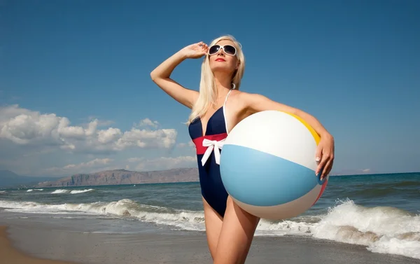 Klämma fast upp flicka med en boll på en strand — Stockfoto