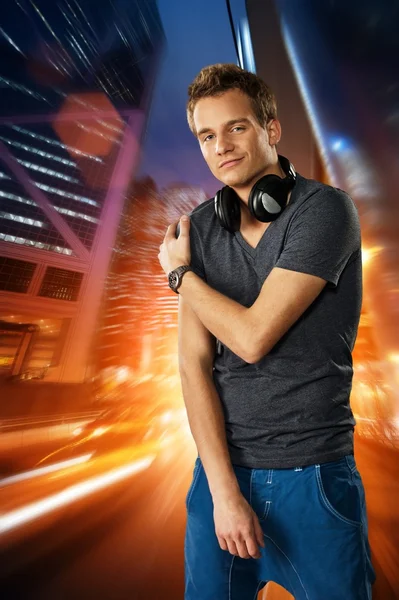 Man with headphones against night city background — Stock Photo, Image