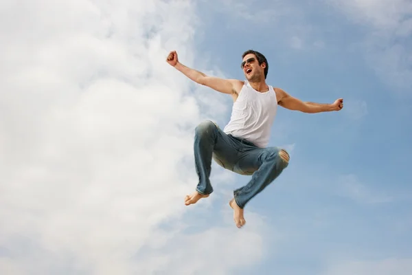 Mutlu genç adam karşı mavi gökyüzü atlama — Stok fotoğraf