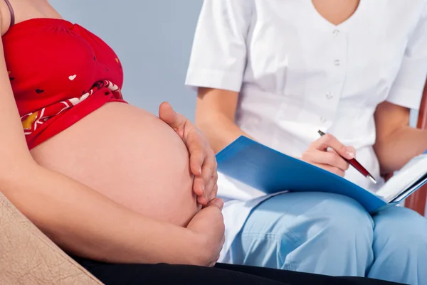 Беременная женщина консультируется с врачом — стоковое фото