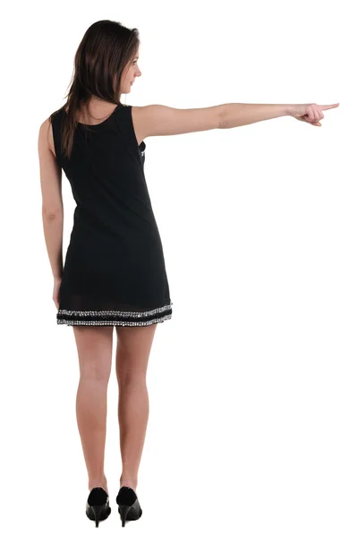 Vacker ung kvinna i klänning pekar på väggen. bakifrån. — Stockfoto