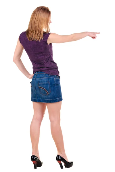 Beautiful young woman in dress pointing at wall. Rear view. — Stock Photo, Image