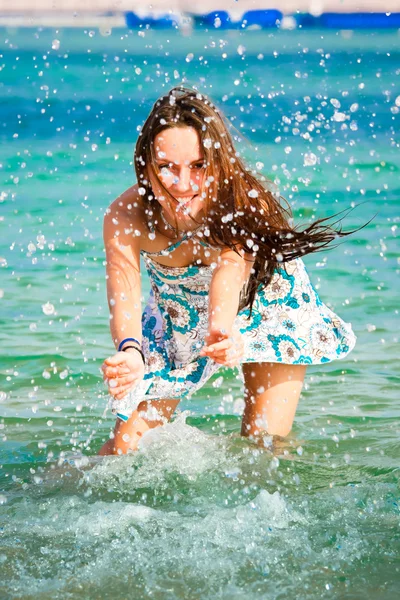 Красивая молодая девушка брызгает водой в море — стоковое фото