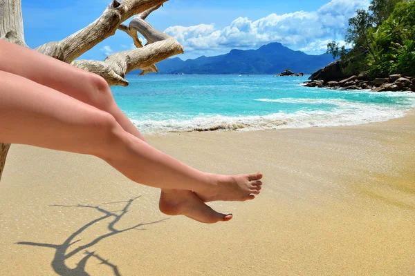 Spiaggia di sabbia, mare azzurro e gambe di donna — Foto Stock