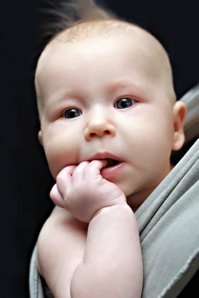 Новорожденный ребенок в серой стропе — стоковое фото