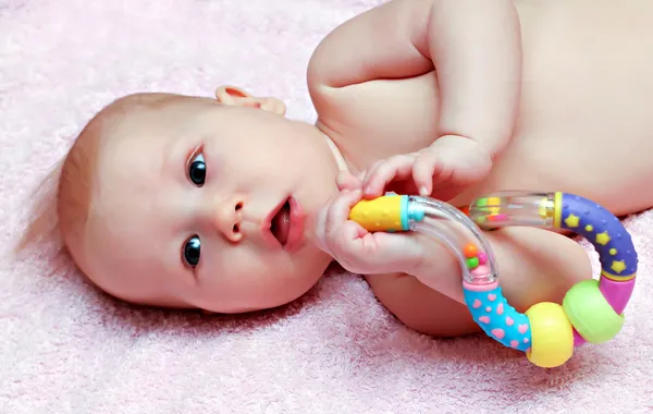 Newborn baby playing with colorful rattle — Stock Photo, Image