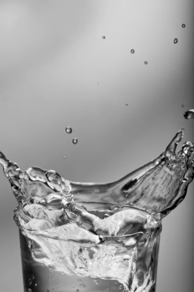 Água doce salpicando de um copo com gelo — Fotografia de Stock