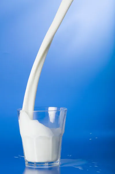 Milch in ein Glas gießen Stockbild