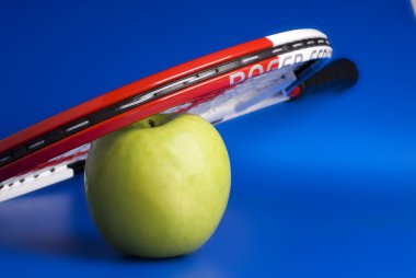 manzana verde y una raqueta de tenis.