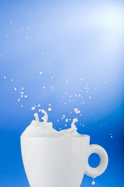 Milk splash out of white cup — Stock Photo, Image