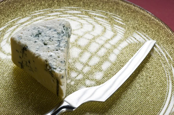 Blauwe kaas en mes op een plaat Stockfoto