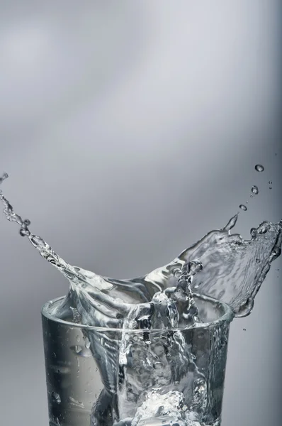 Fresh water splashing out of a glass with ice — Stock Photo, Image