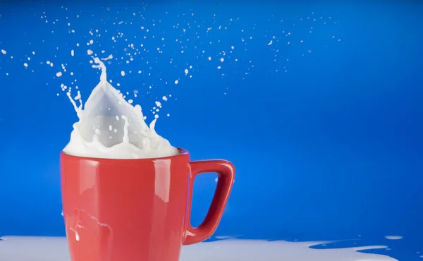 Milk splash out of red cup — Stock Photo, Image