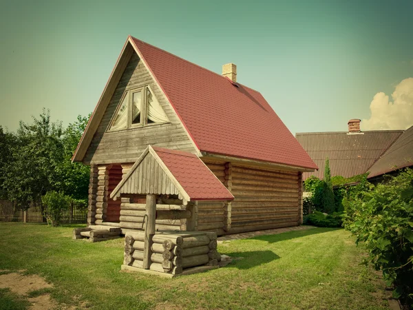 Casa de madeira e bem no pátio — Fotografia de Stock