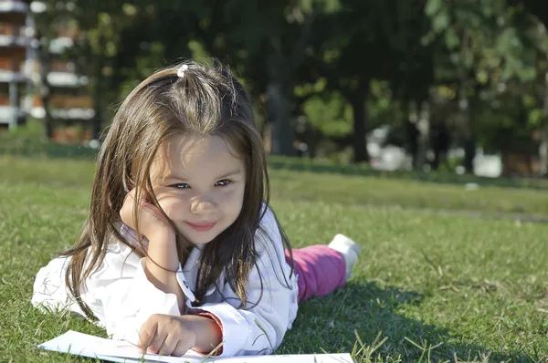 Dívka v trávě a čtení — Stock fotografie