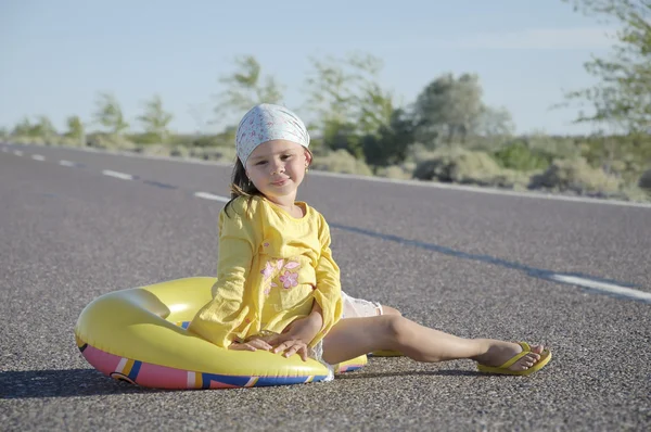 Petite fille assise sur une route asphaltée — Photo