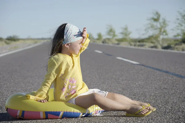 Menina sentada na estrada asfaltada — Fotografia de Stock