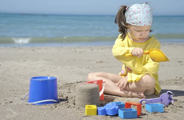 Dívka si hraje s hračkami na písčité pláži — Stock fotografie