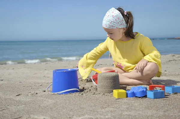 Girl playing with toys on sand beach — Stock Photo, Image