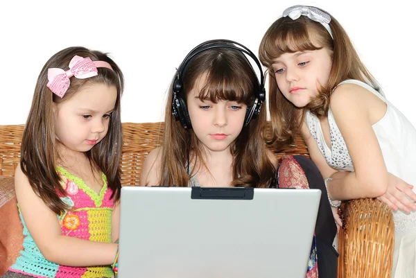 Tre bambina in cuffia con computer portatile — Foto Stock