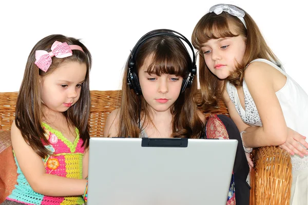 Tre liten flicka i hörlurar med laptop — Stockfoto