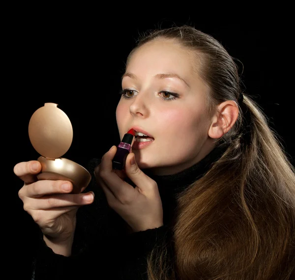 Het meisje doet een make-up voor een spiegel — Stockfoto
