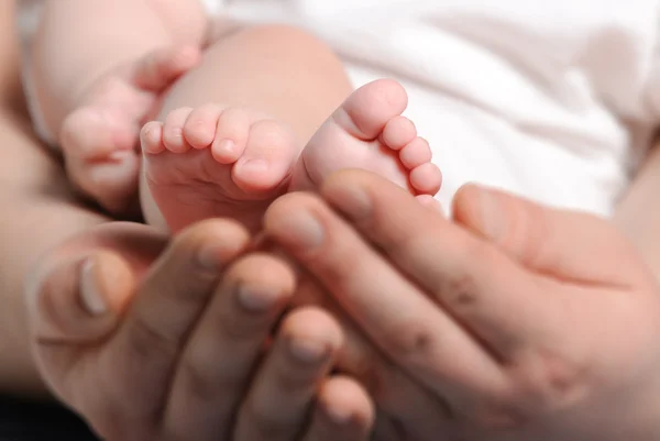 Pés o bebê em mãos adultas — Fotografia de Stock