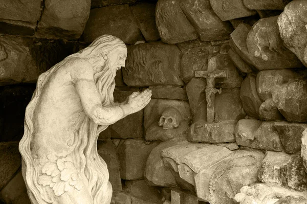 Monumento rezando ancião em uma caverna — Fotografia de Stock