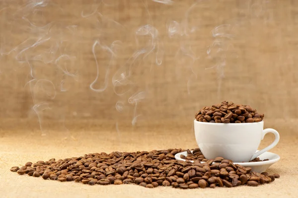 Cup with grains of coffee and a smoke. — Stock Photo, Image