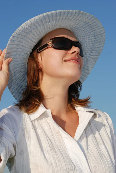 在眼镜和帽子的天空背景上的女人 — 图库照片