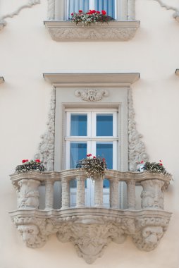 Facade of a building with a balcony and flowers clipart