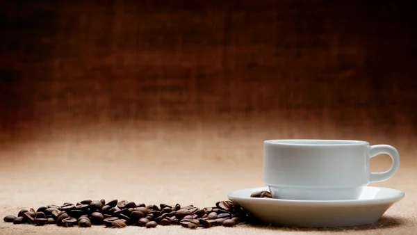 Taça branca c grãos de café no grunge um fundo — Fotografia de Stock