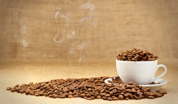 Cup with grains of coffee and a smoke. — Stock Photo, Image