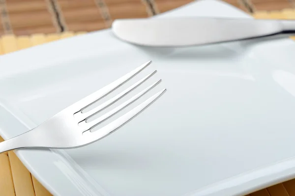 Fork and a knife laying on a plate — Stock Photo, Image
