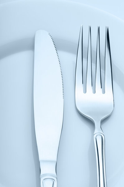 Knife and fork on a plate. Kitchen accessories close up