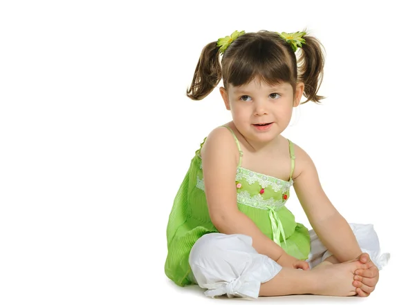 Pretty the little girl sits on the white — Stock Photo, Image