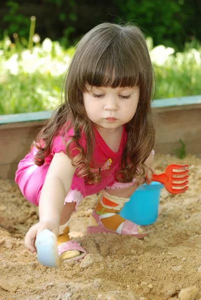 Das Mädchen, das an einem Sandkasten spielt — Stockfoto