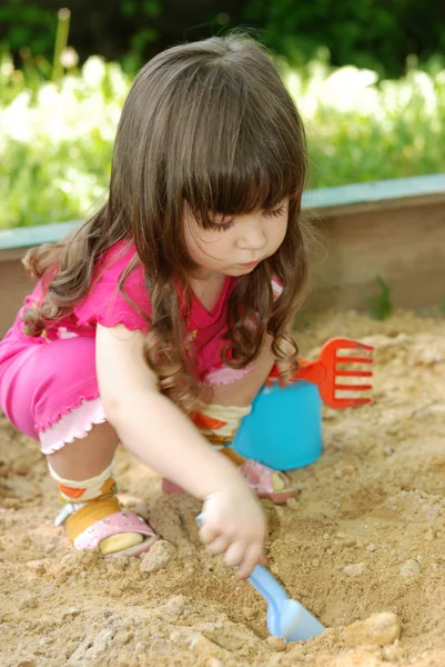 The girl playing to a sandbox — Stock Photo, Image