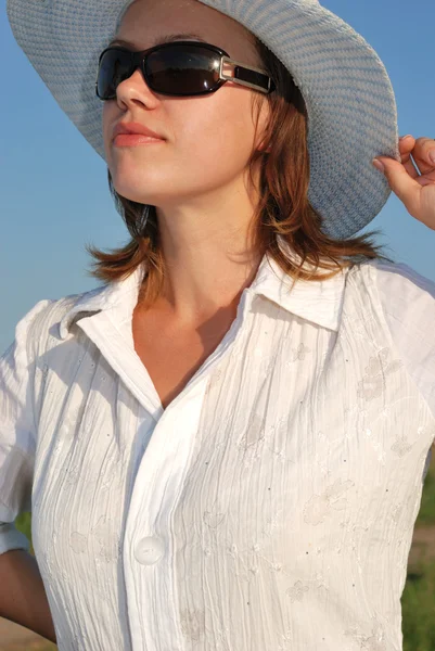 La mujer en gafas y un sombrero sobre un fondo del cielo —  Fotos de Stock